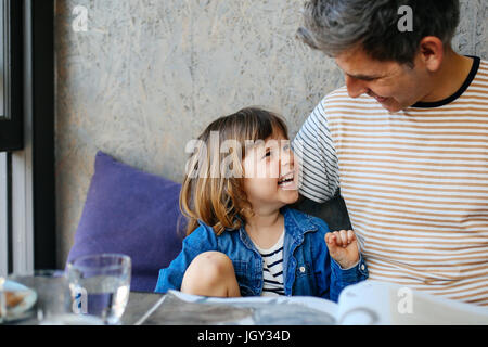 Girl laughing with father in cafe Stock Photo
