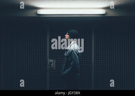 Young male hipster in dark city doorway at night Stock Photo