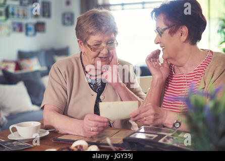 Two senior women chatting while looking at old photographs at table Stock Photo