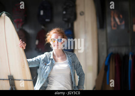Woman working in board shop, holding surfboard Stock Photo