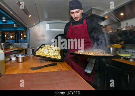 Chef preparing pizzas in food stall van at night Stock Photo