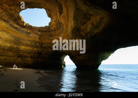 Mother and son standing in the light in the rock cave of Benagil, Algarve, Portugal. Stock Photo