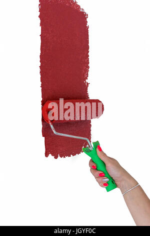 A red paint roller applying color to wooden surface with vivid texture ...