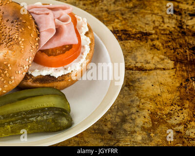Ham Tomato and Cheese Sesame Bagel With Gherkins Sitting on an Oven Tray Stock Photo