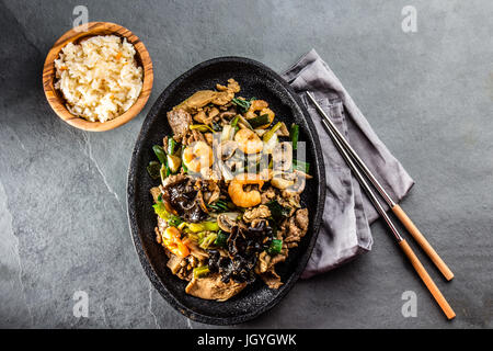Chinese food. Te pam sao. Pan of fried beef, pork, chicken, shrimps, shiitake mushroom, champions and spring onion. Parillada china served with rice o Stock Photo