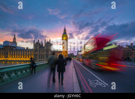 London, England - Iconic Red Double Decker Bus on the move on Westminster Bridge with Big Ben and Houses of Parliament at background. Sunset with beau Stock Photo