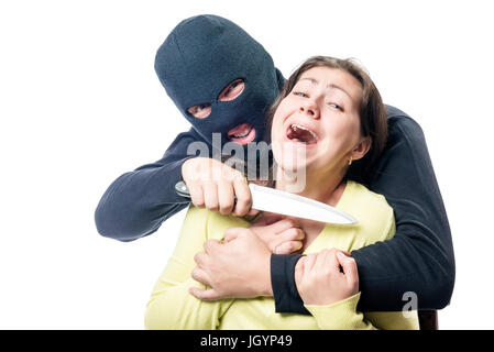 A terrorist in a balaclava threatens a victim with a knife against a white background Stock Photo