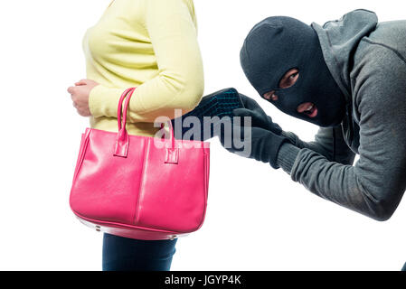 A thief pickpocket steals a purse from a women's bag in a balaclava Stock Photo