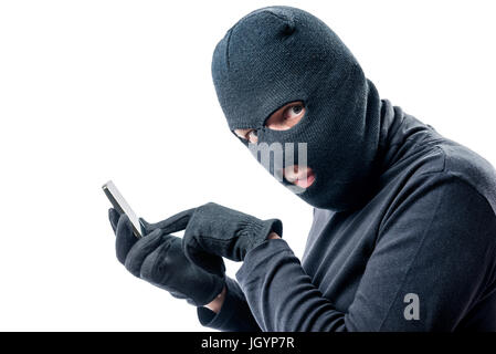 Hacker hacks data from a mobile phone on a white background in a mask Stock Photo