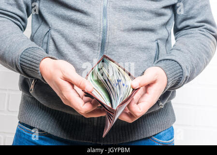 A leather purse in men's hands is full of dollars Stock Photo