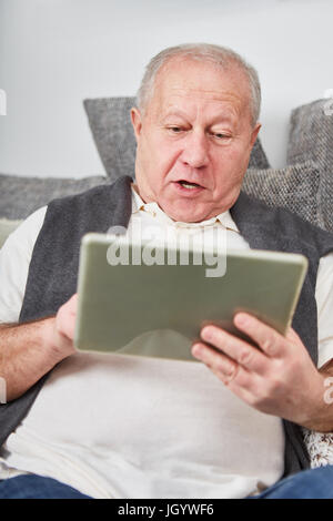 Senior looks at tablet with amazement while surfing the internet Stock Photo