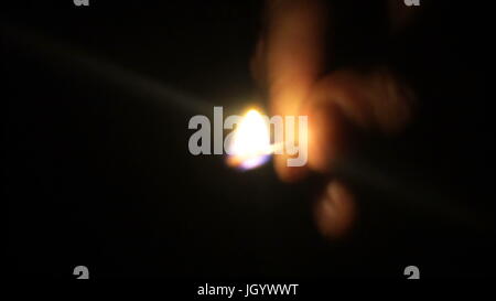 Man lights a match in darkness. Slow Motion. Stock Photo