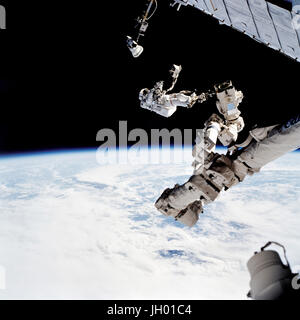 Astronaut David A. Wolf, STS-112 mission specialist, anchored to a foot restraint on the Space Station Remote Manipulator System (SSRMS) or Canadarm2, carries the Starboard One (S1) outboard nadir external camera. The camera was installed on the end of the S1 Truss on the International Space Station (ISS) during the mission's first scheduled session of extravehicular activity (EVA). NASA Photo Stock Photo