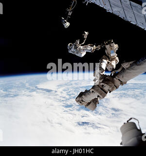 Astronaut David A. Wolf, STS-112 mission specialist, anchored to a foot restraint on the Space Station Remote Manipulator System (SSRMS) or Canadarm2, carries the Starboard One (S1) outboard nadir external camera. The camera was installed on the end of the S1 Truss on the International Space Station (ISS) during the mission's first scheduled session of extravehicular activity (EVA). Stock Photo