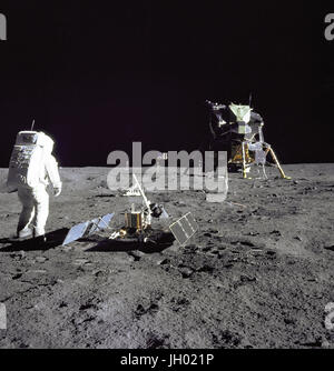 Aldrin Looks Back at Tranquility Base. Astronaut Edwin E.'Buzz' Aldrin Jr., Lunar Module pilot, is photographed during the Apollo 11 extravehicular activity on the Moon. He has just deployed the Early Apollo Scientific Experiments Package (EASEP). In the foreground is the Passive Seismic Experiment Package (PSEP); beyond it is the Laser Ranging Retro-Reflector (LR-3); in the center background is the United States flag; in the left background is the black and white lunar surface television camera.