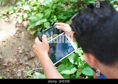 Los Angeles, USA - July 9, 2017:Man using DJI mavic drone controller with tablet. Man flying over beach Stock Photo