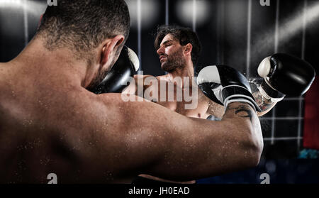 Boxer punches his opponent during boxing competition Stock Photo
