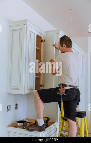 Installation of kitchen. Worker installs doors to kitchen cabinet. Installation of doors on kitchen cabinets Stock Photo