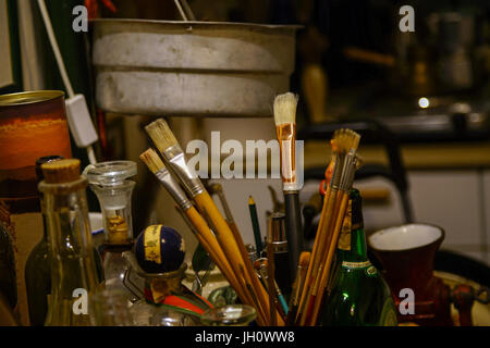 Artist's paint brushes in container on a worktable Stock Photo
