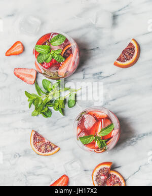 Blood orange and strawberry summer Sangria. Fruit refreshing rose wine cocktails in glasses with ice and mint over grey marble background, top view Stock Photo
