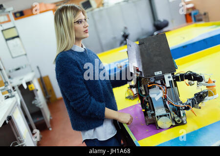 Young beautiful female engineer testing robot in workshop Stock Photo