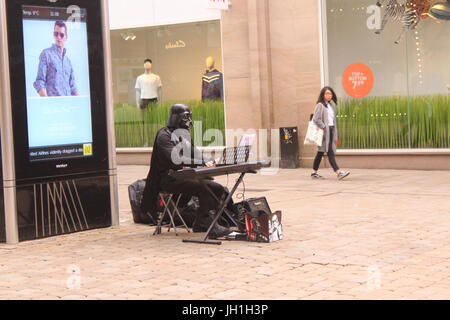 Female shopper watches Darth Vader playing Keyboard in Manchester City Centre Stock Photo