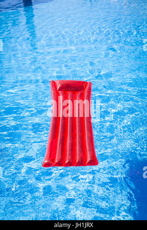 Red inflatable lilo lounger floating in a swimming pool Stock Photo