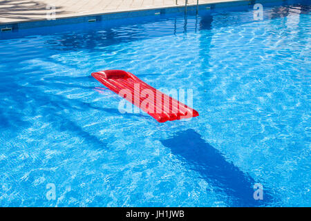 Red inflatable lilo lounger floating in a swimming pool Stock Photo