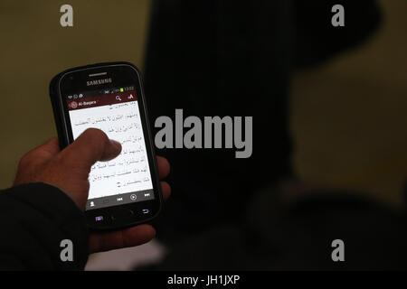 Man reading the Quran on a smartphone.  France. Stock Photo
