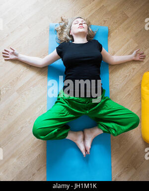 Middle aged or mature woman doing yoga indoors Stock Photo