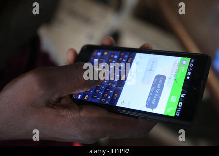 Close up of an african  man using a smart phone with a cracked screen.     Lome. Togo. Stock Photo