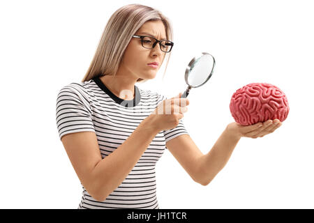 Young woman examining a brain model with a magnifying glass isolated on white background Stock Photo