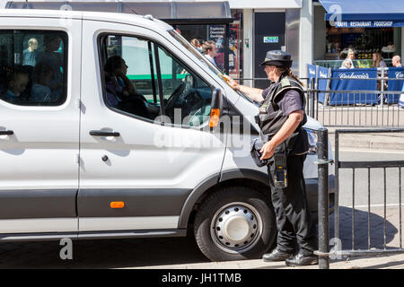 Traffic warden issuing a parking ticket and attaching it to a vehicle for illegal parking, West Bridgford, Nottinghamshire, England, UK Stock Photo