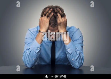 white collar crime concept - desperate businessman with handcuffs Stock Photo