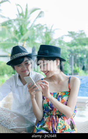 beautiful asian younger woman toothy smiling face and playing on smart phone screen Stock Photo