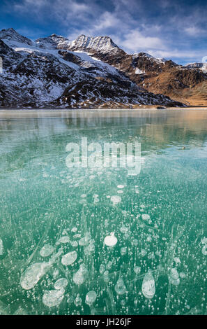 Ice bubbles in the turquoise water of the frozen White Lake (Lago Bianco), Bernina Pass, Canton of Graubunden, Switzerland Stock Photo
