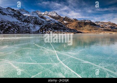 The snowy peaks frame the frozen turquoise water of White Lake, Bernina Pass, Canton of Graubunden, Engadine, Switzerland Stock Photo