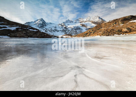 Blue sky and clouds on frozen Lej Nair surrounded by snowy peaks, Bernina Pass, Canton of Graubunden, Engadine, Switzerland Stock Photo