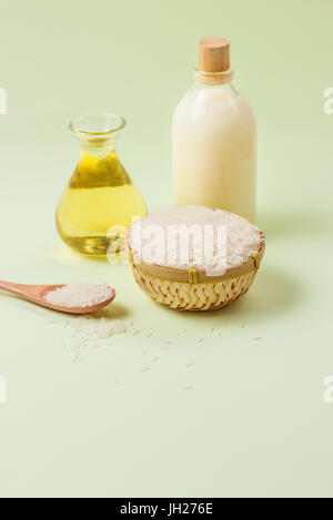 Rice oil in bottle glass and milk over green background. Stock Photo