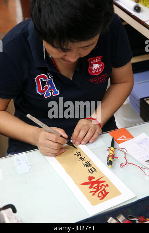 Chinese handicrafts for sale in Chinatown. Calligraphy artist.  Singapore. Stock Photo