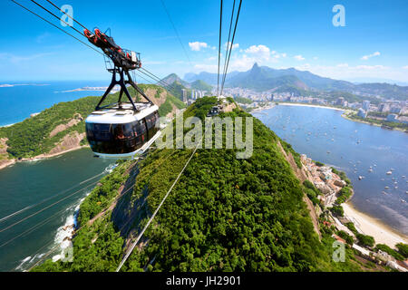 A cable car approaches the station atop Sugarloaf mountain, with a view of Rio de Janeiro behind, Rio de Janeiro, Brazil Stock Photo