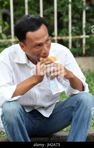 Man eating a sandwich. Ho Chi Minh City. Vietnam. Stock Photo