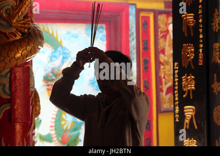 Chua On Lang taoist temple. Buddhist Worshipper. Burning incense sticks.  Ho chi Minh City. Vietnam. Stock Photo