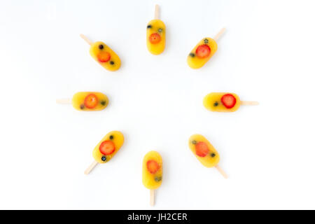 Homemade fruit ice pop, popsicle, ice cream lolly with orange juice, fresh strawberries and blueberries arranged in a circle on a white background wit Stock Photo