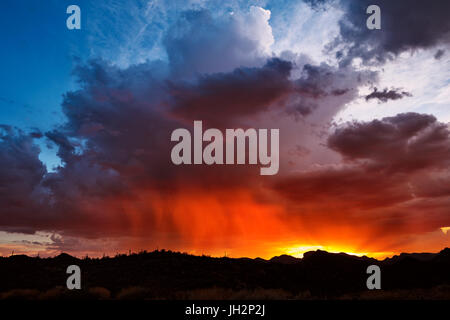 A fiery desert sunset sky near Lake Pleasant as monsoon storm clouds drifted off the Bradshaw Mountains in Phoenix, Arizona, USA Stock Photo