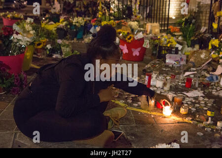 London, UK. 12th July 2017. A teen age girl lights a candle during vigil to mark four weeks since the Grenfell Tower fire. Credit: Thabo Jaiyesimi/Alamy Live News Stock Photo