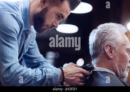 Nice male hairdresser being focused on his job Stock Photo