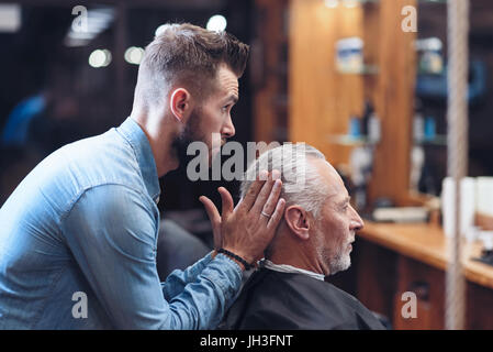 Nice professional barber modeling a hairstyle Stock Photo