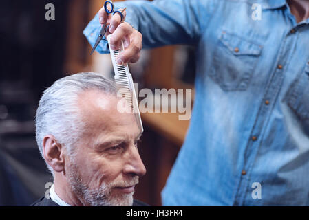 Professional male barber combing his customers hair Stock Photo