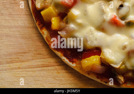 A vegetable and mozzarella pizza shot from above on a scratched wooden board with copy space to the left. Stock Photo